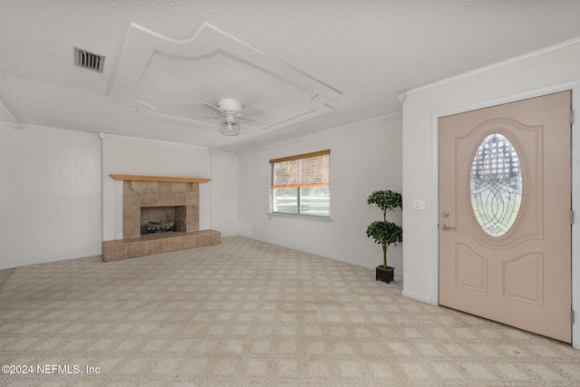 foyer featuring ceiling fan, light colored carpet, a tile fireplace, and a textured ceiling