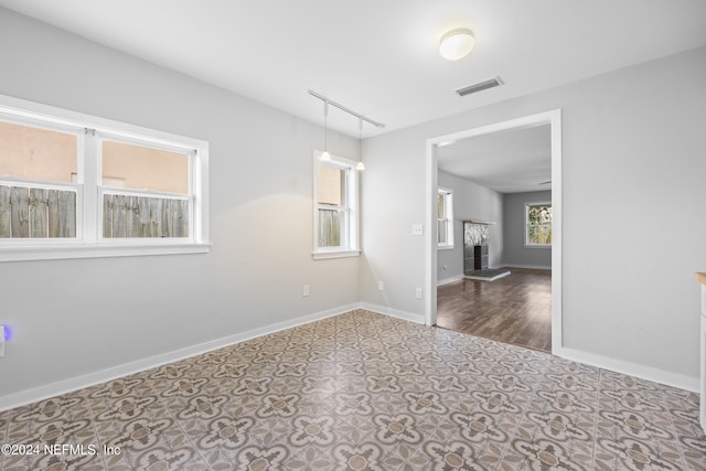 empty room with dark hardwood / wood-style flooring and rail lighting