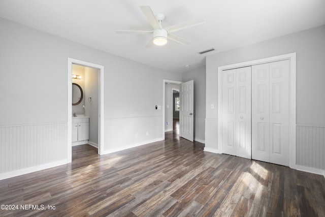 unfurnished bedroom featuring ensuite bath, ceiling fan, a closet, and dark wood-type flooring