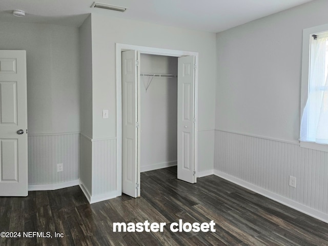 unfurnished bedroom featuring dark hardwood / wood-style floors and a closet