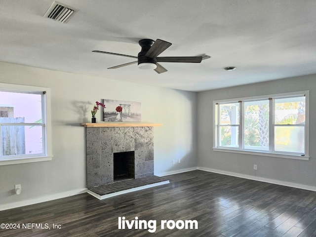 unfurnished living room featuring a tiled fireplace, ceiling fan, and dark hardwood / wood-style flooring