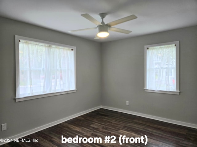 spare room with plenty of natural light, ceiling fan, and dark hardwood / wood-style flooring