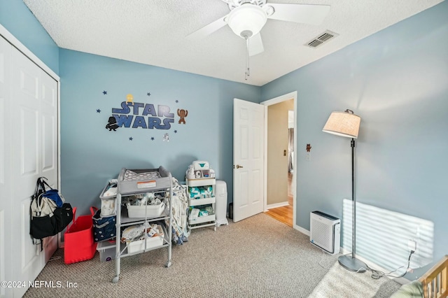 carpeted bedroom featuring ceiling fan and a textured ceiling