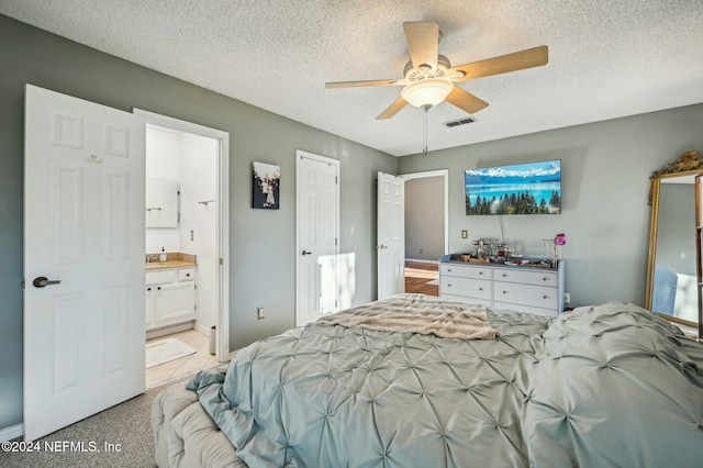 carpeted bedroom featuring connected bathroom, ceiling fan, and a textured ceiling