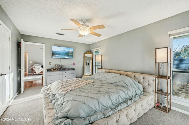 carpeted bedroom with ceiling fan and a textured ceiling