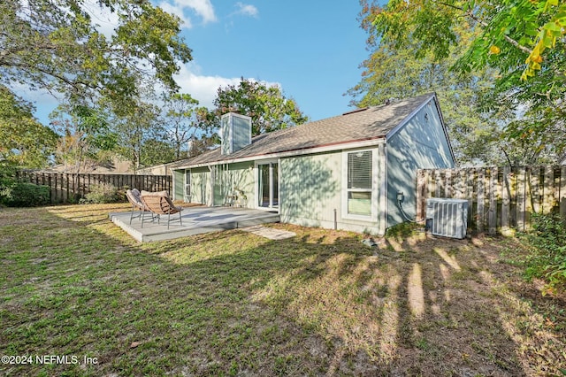 rear view of property featuring central air condition unit, a patio area, and a lawn