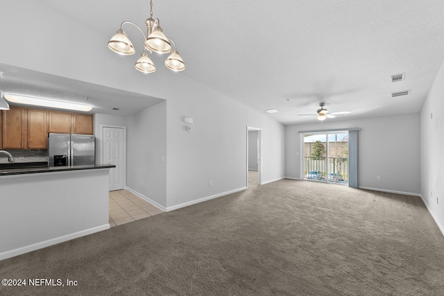 unfurnished living room featuring ceiling fan with notable chandelier, light colored carpet, and a textured ceiling