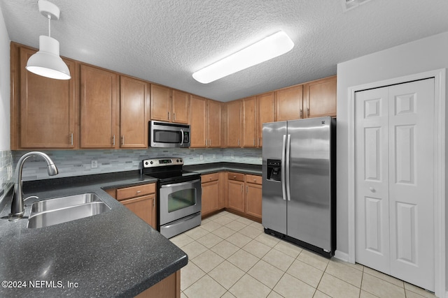 kitchen with sink, hanging light fixtures, decorative backsplash, light tile patterned floors, and appliances with stainless steel finishes