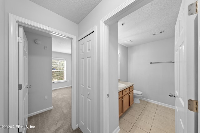 bathroom with tile patterned flooring, vanity, toilet, and a textured ceiling