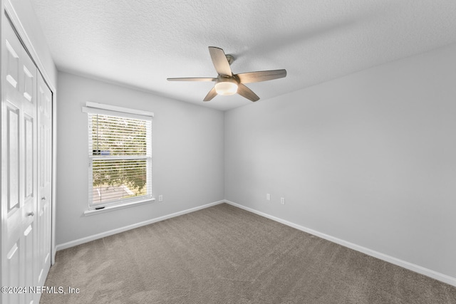 empty room with ceiling fan, carpet, and a textured ceiling