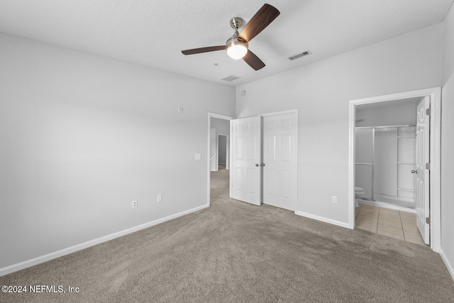 unfurnished bedroom with a textured ceiling, ceiling fan, ensuite bathroom, and light carpet