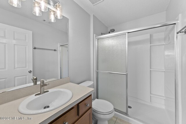 bathroom featuring tile patterned flooring, a textured ceiling, toilet, and an enclosed shower