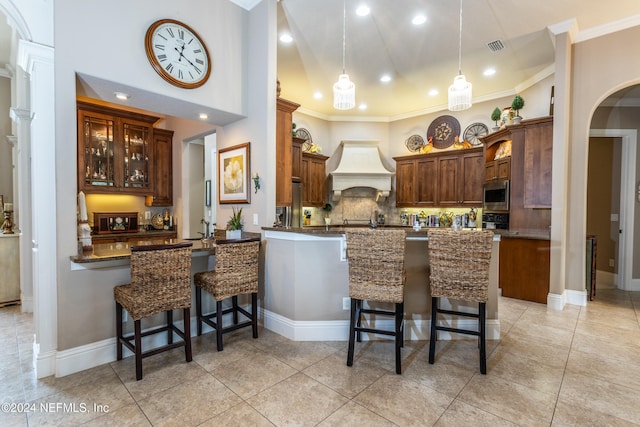 kitchen with custom exhaust hood, stainless steel microwave, hanging light fixtures, tasteful backsplash, and kitchen peninsula