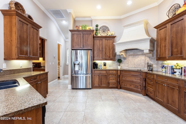 kitchen with stainless steel fridge, custom range hood, crown molding, sink, and light tile patterned floors