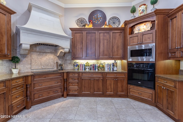 kitchen with premium range hood, dark stone counters, black appliances, and ornamental molding