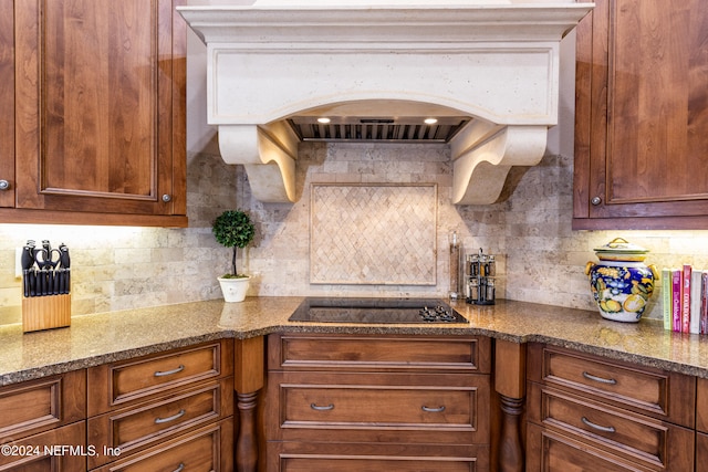 kitchen featuring backsplash, black electric cooktop, and light stone countertops