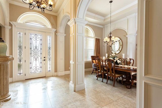 foyer with decorative columns, crown molding, a healthy amount of sunlight, and a notable chandelier