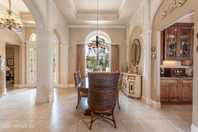 dining area with a notable chandelier, ornate columns, ornamental molding, and a tray ceiling