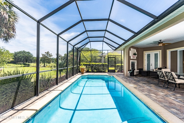 view of pool featuring ceiling fan, a patio, glass enclosure, and french doors