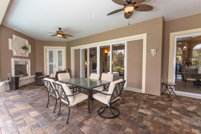 dining room featuring ceiling fan, a tiled fireplace, and french doors