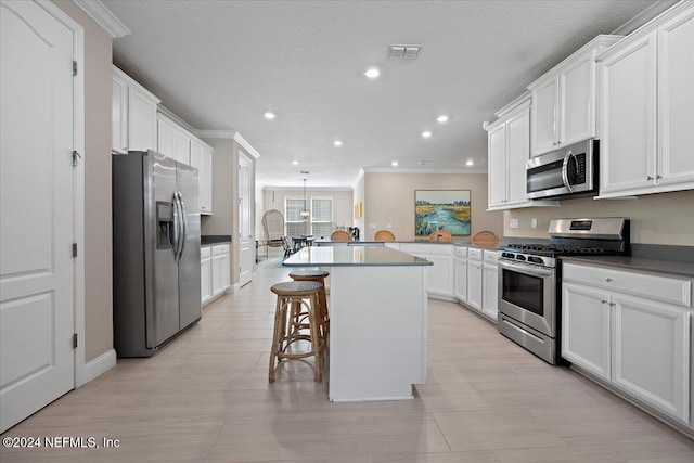 kitchen featuring a breakfast bar, a center island, appliances with stainless steel finishes, white cabinetry, and kitchen peninsula