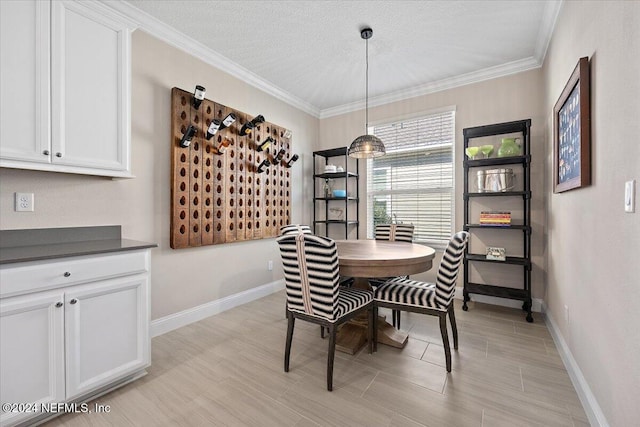 dining room featuring light wood-type flooring, a textured ceiling, and ornamental molding