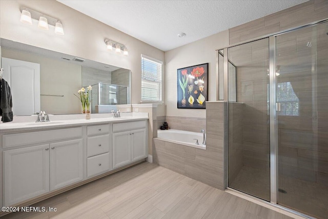 bathroom with plus walk in shower, a textured ceiling, and vanity