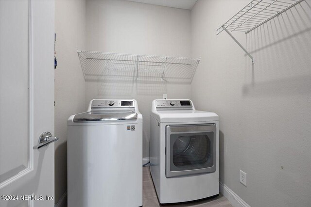 laundry area with washing machine and dryer and light tile patterned flooring