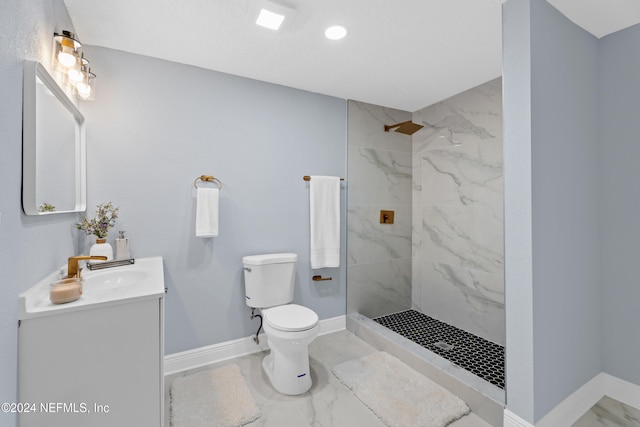 bathroom featuring a tile shower, vanity, and toilet