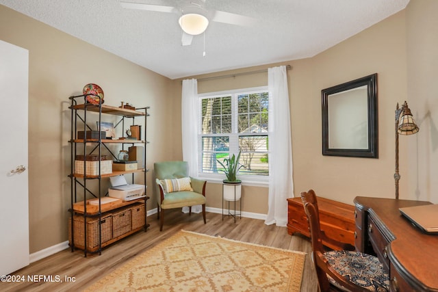 living area with a textured ceiling, light hardwood / wood-style flooring, and ceiling fan