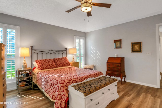 bedroom with hardwood / wood-style floors, a textured ceiling, and ceiling fan