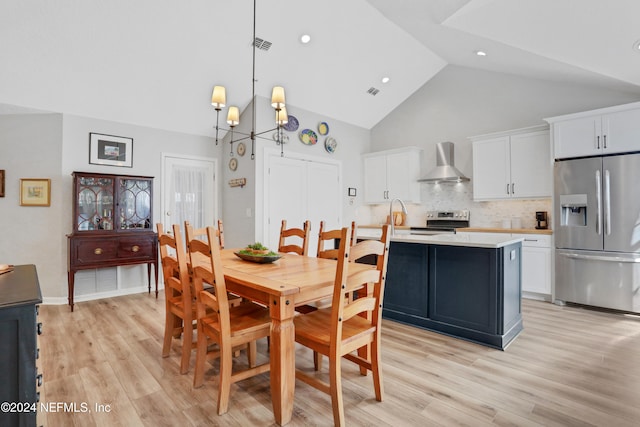 dining space featuring a notable chandelier, light hardwood / wood-style floors, sink, and high vaulted ceiling