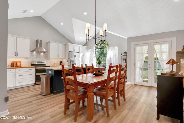 dining room with a notable chandelier, french doors, high vaulted ceiling, and light hardwood / wood-style flooring