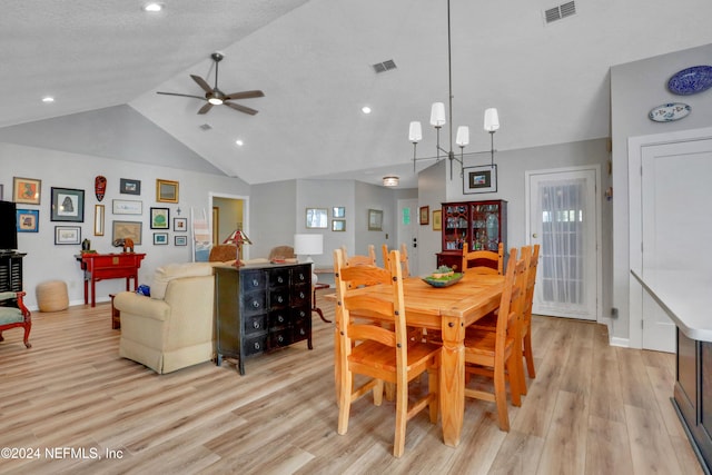 dining space featuring a textured ceiling, ceiling fan with notable chandelier, light hardwood / wood-style flooring, and lofted ceiling