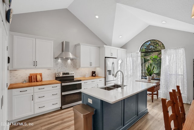 kitchen with wall chimney exhaust hood, white cabinetry, and stainless steel appliances