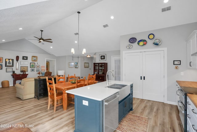 kitchen with blue cabinetry, hanging light fixtures, light hardwood / wood-style flooring, lofted ceiling, and a kitchen island with sink