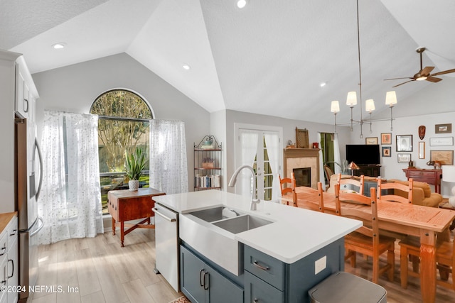 kitchen with white cabinetry, sink, vaulted ceiling, a tiled fireplace, and appliances with stainless steel finishes