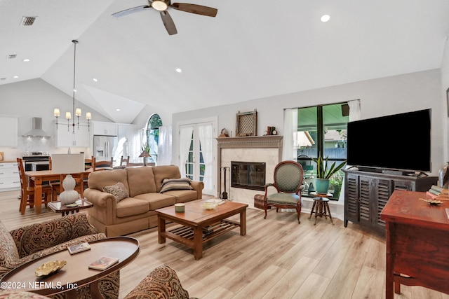 living room featuring ceiling fan with notable chandelier, light hardwood / wood-style floors, high vaulted ceiling, and a premium fireplace