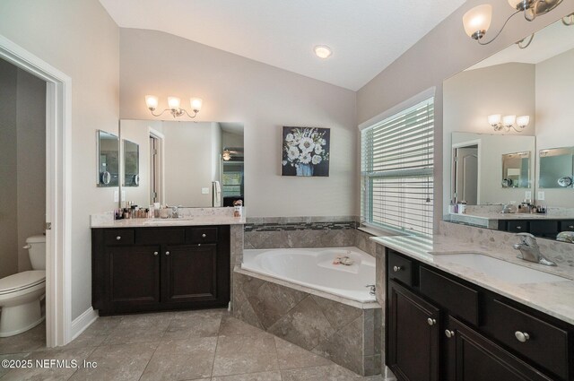 bathroom with a sink, a garden tub, lofted ceiling, and toilet