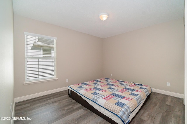 bedroom featuring baseboards and dark wood-style flooring