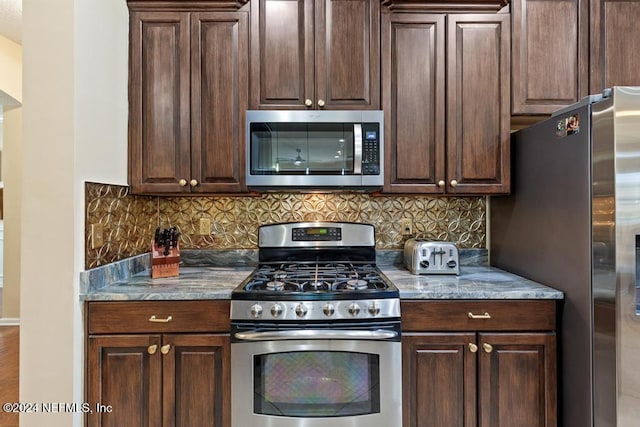 kitchen featuring decorative backsplash, light stone counters, dark brown cabinetry, and stainless steel appliances