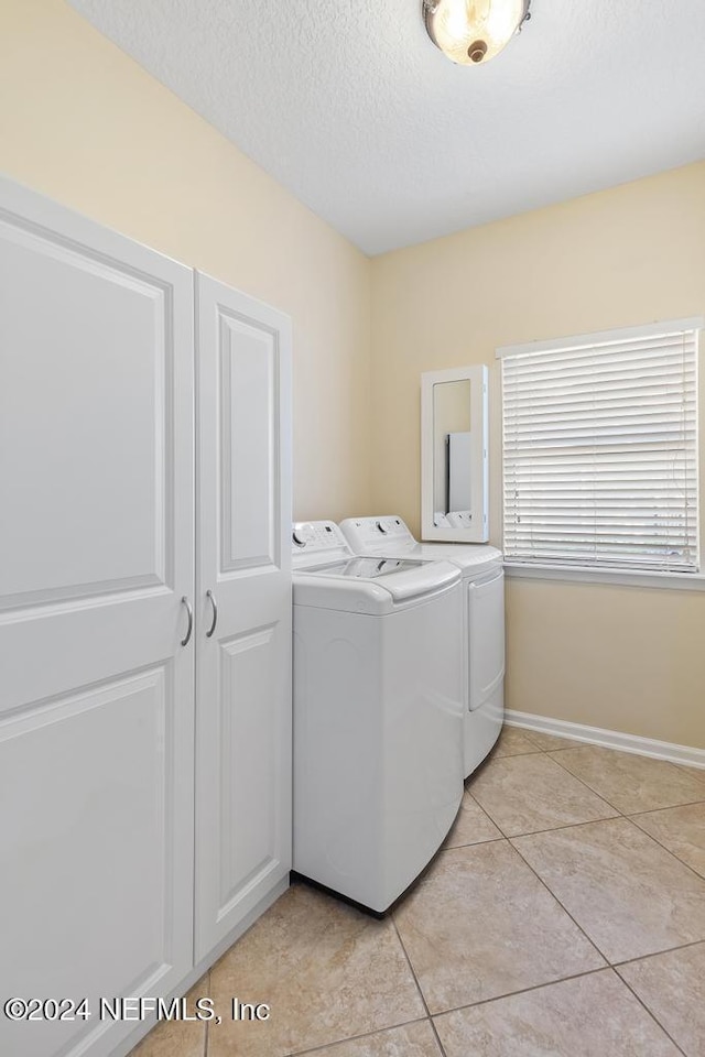 laundry area with separate washer and dryer, light tile patterned floors, and a textured ceiling