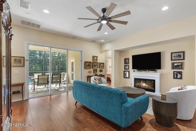 living room with ceiling fan, dark hardwood / wood-style flooring, and a textured ceiling