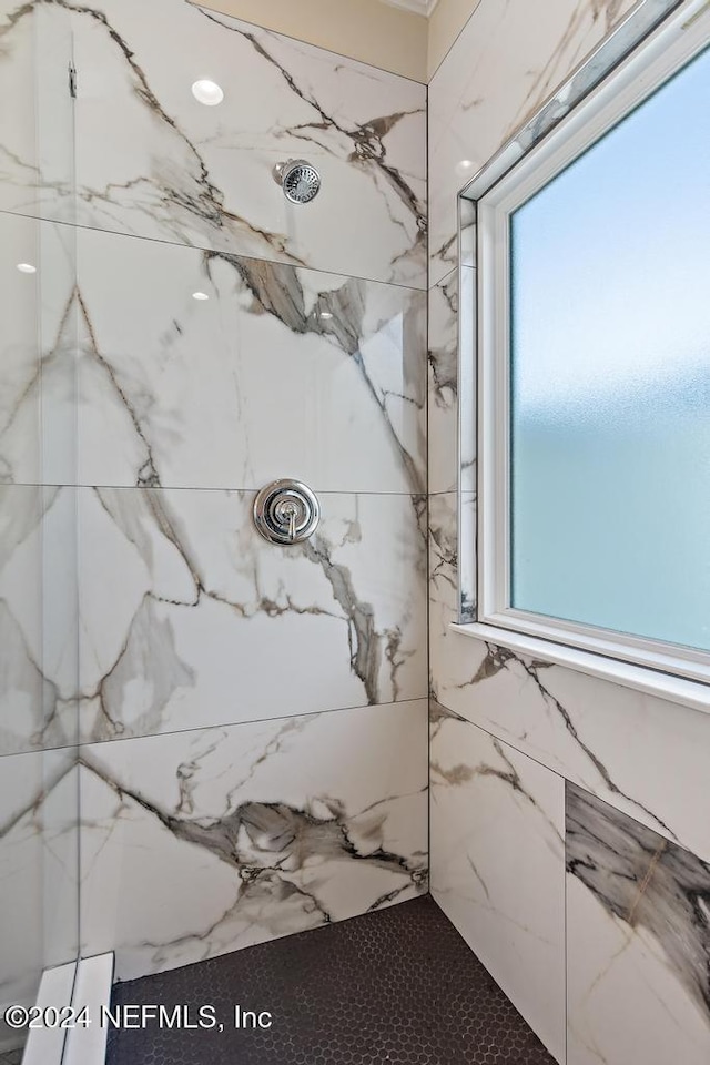 bathroom with a healthy amount of sunlight and tiled shower