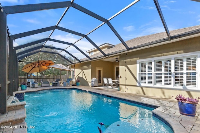 view of swimming pool featuring a lanai, a patio area, pool water feature, and ceiling fan