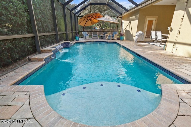 view of swimming pool with pool water feature, glass enclosure, and a patio area