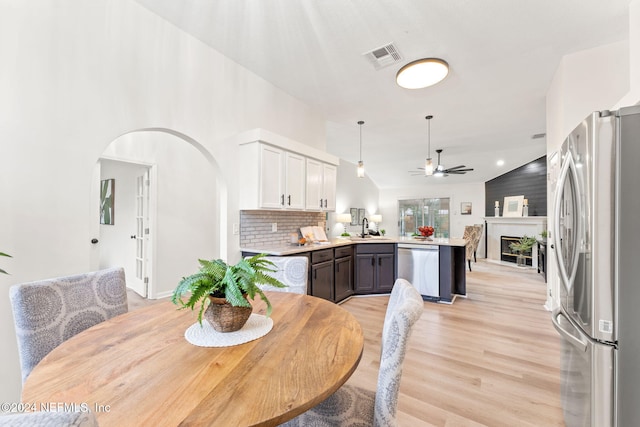 dining area featuring ceiling fan, lofted ceiling, sink, and light hardwood / wood-style flooring