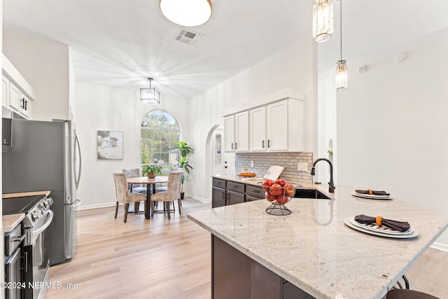 kitchen featuring light stone countertops, pendant lighting, white cabinets, and stainless steel range with electric cooktop