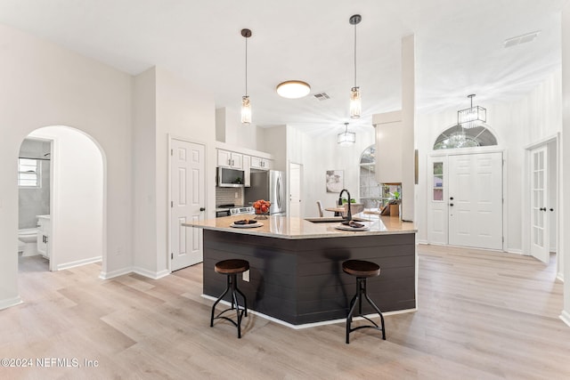 kitchen featuring a breakfast bar, white cabinets, sink, light hardwood / wood-style flooring, and appliances with stainless steel finishes