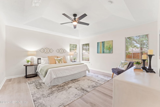 bedroom featuring light hardwood / wood-style floors, a raised ceiling, and ceiling fan